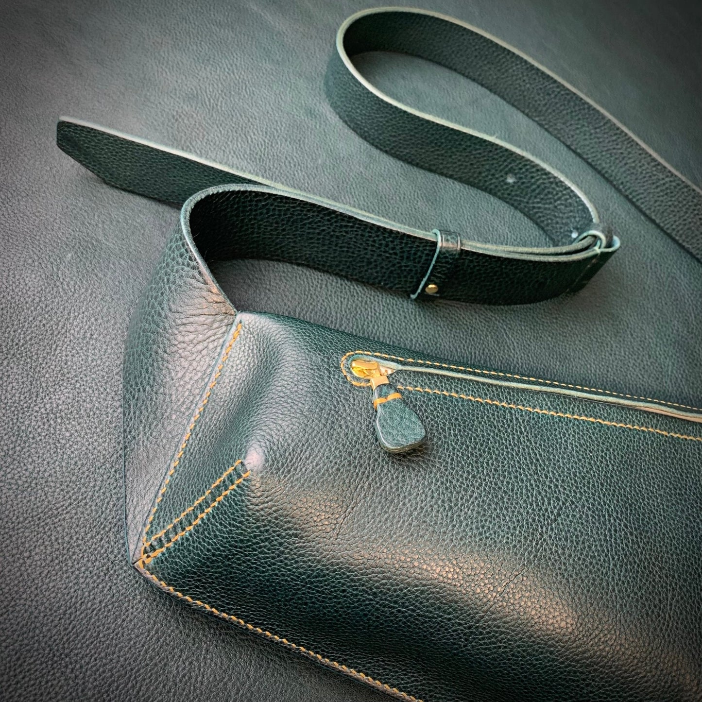 leather zip pull detail on the keep-studio handmade elton bag in petrol with mustard hand stitching