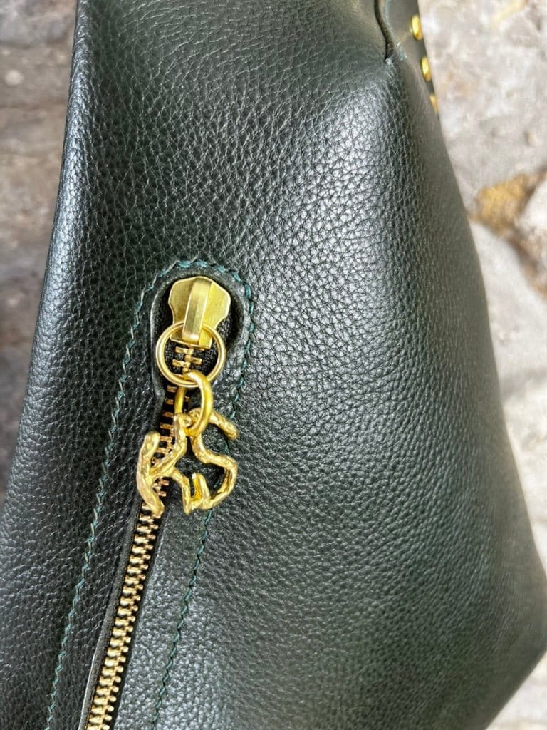close up of the brass branded zip pull on keep studio bag