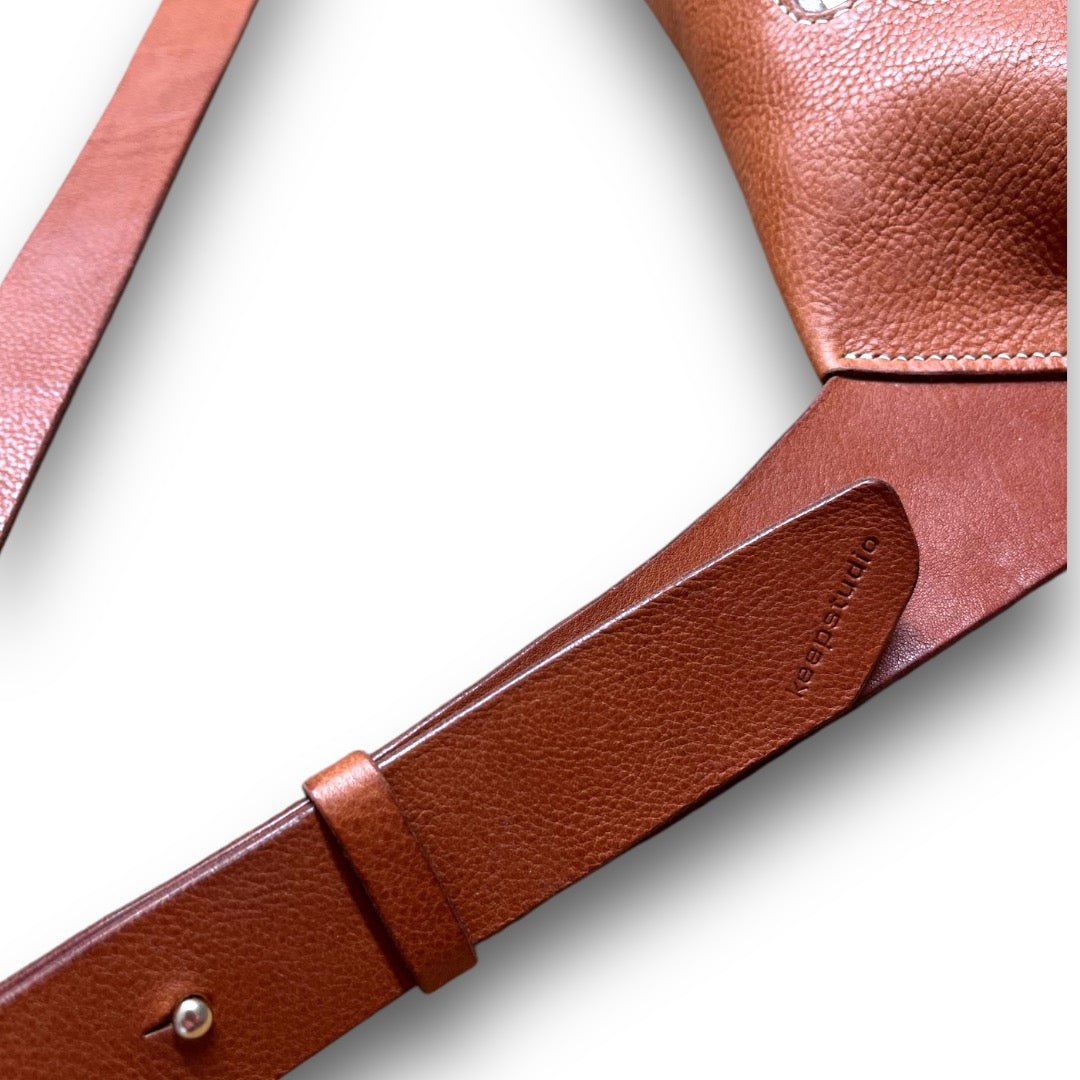 close up of the adjustable strap on a bag. showing sam browne stud detail and embossed logo