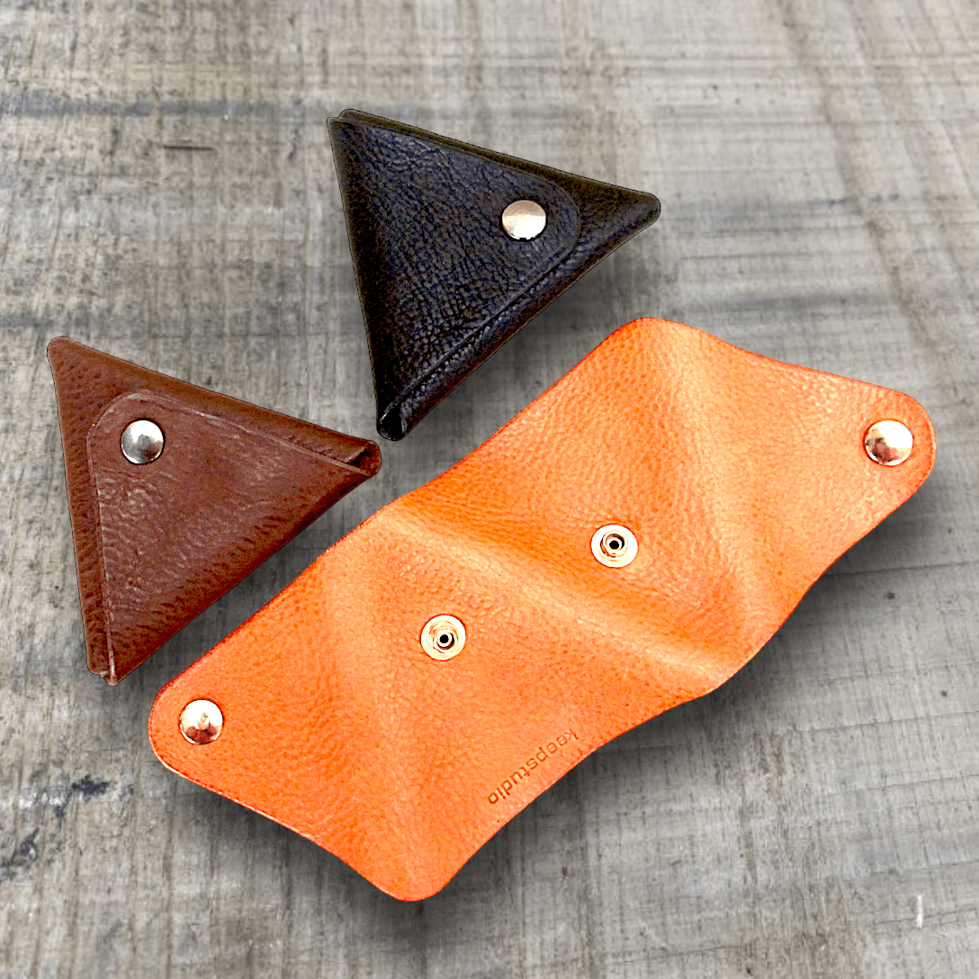 Three traingle coin purses in shade of tan and brown showing the simple contruction of one piece of leather