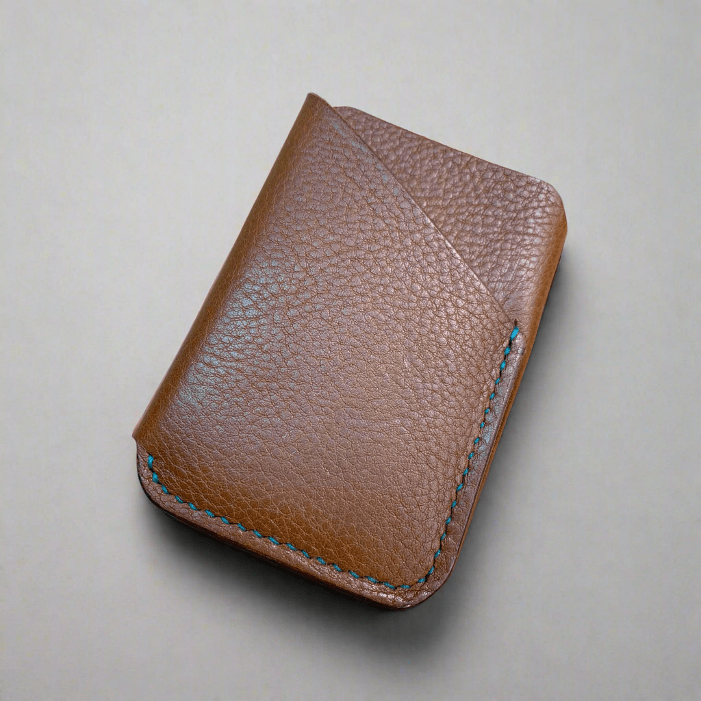 A hand made leather card wallet with wrap design in broen leather with teal hand stitching