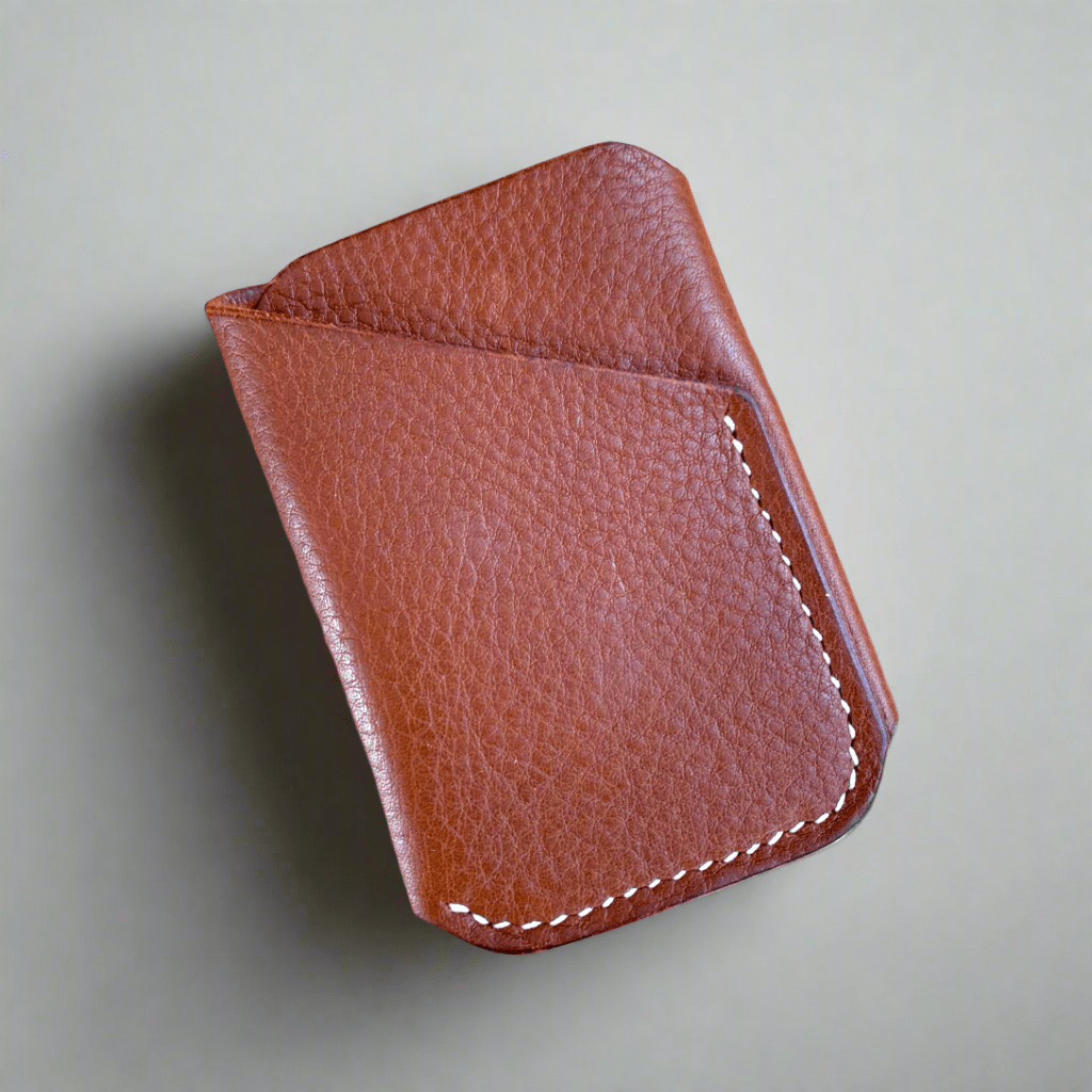 A dark tan leather card wallet made from a single piece of veg tanned lather sewn in cream thread