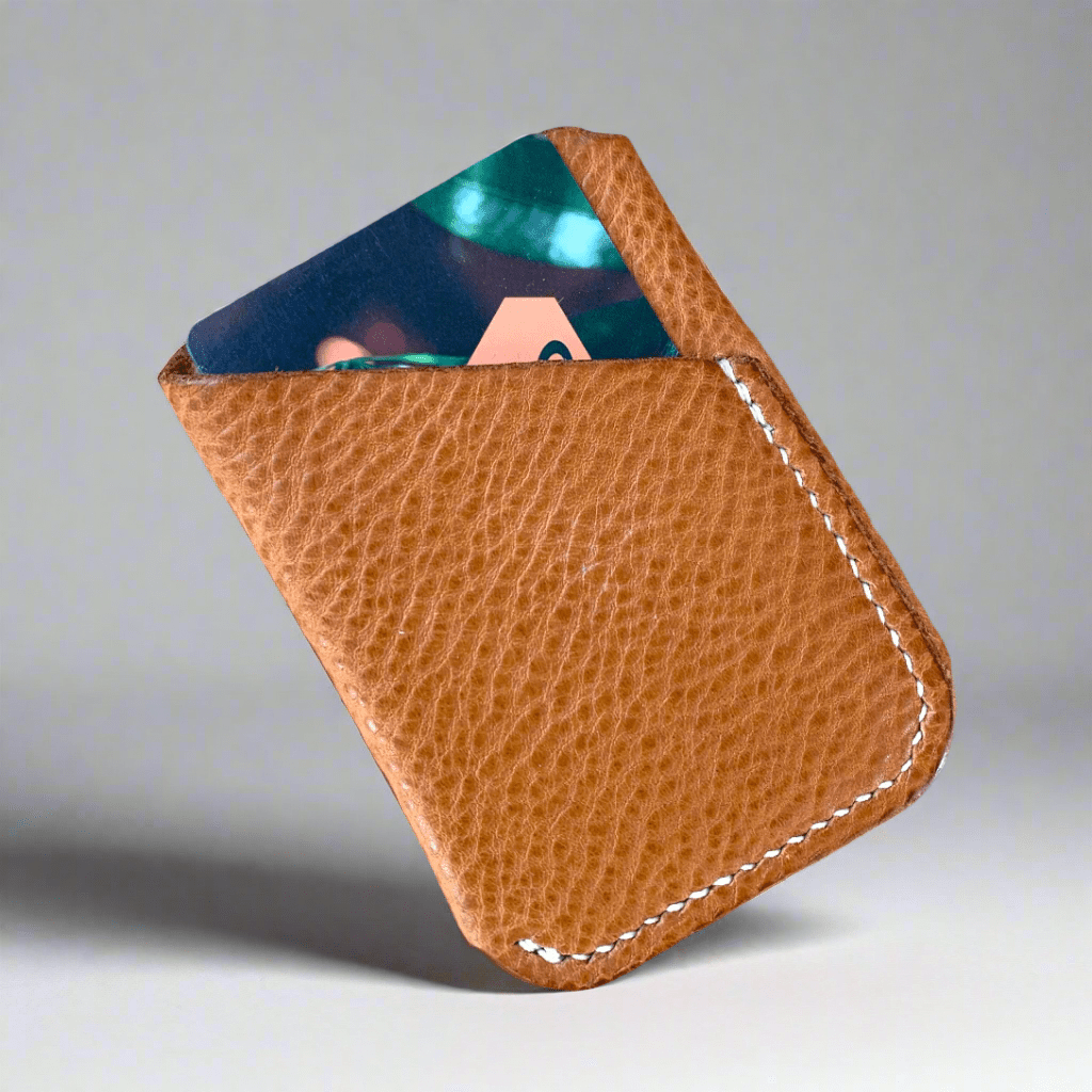 A wrap style card wallet in light tan tumbled leather with a credit card inside