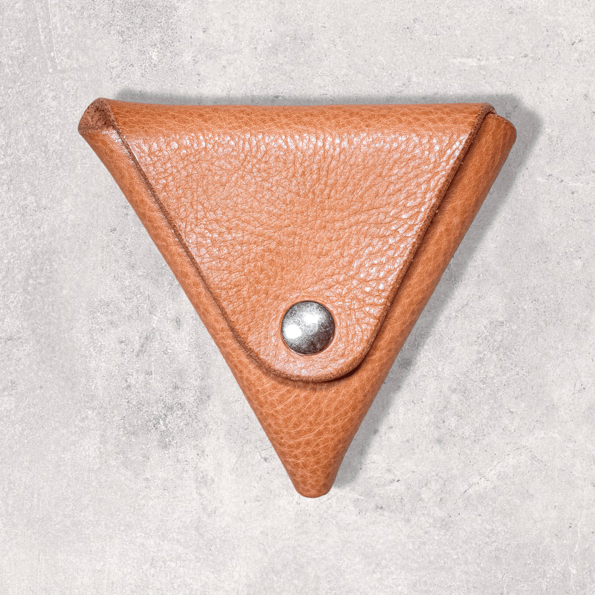 A coin purse made from a single piece of leather folded into a triangle. Light tan leather with brass popper
