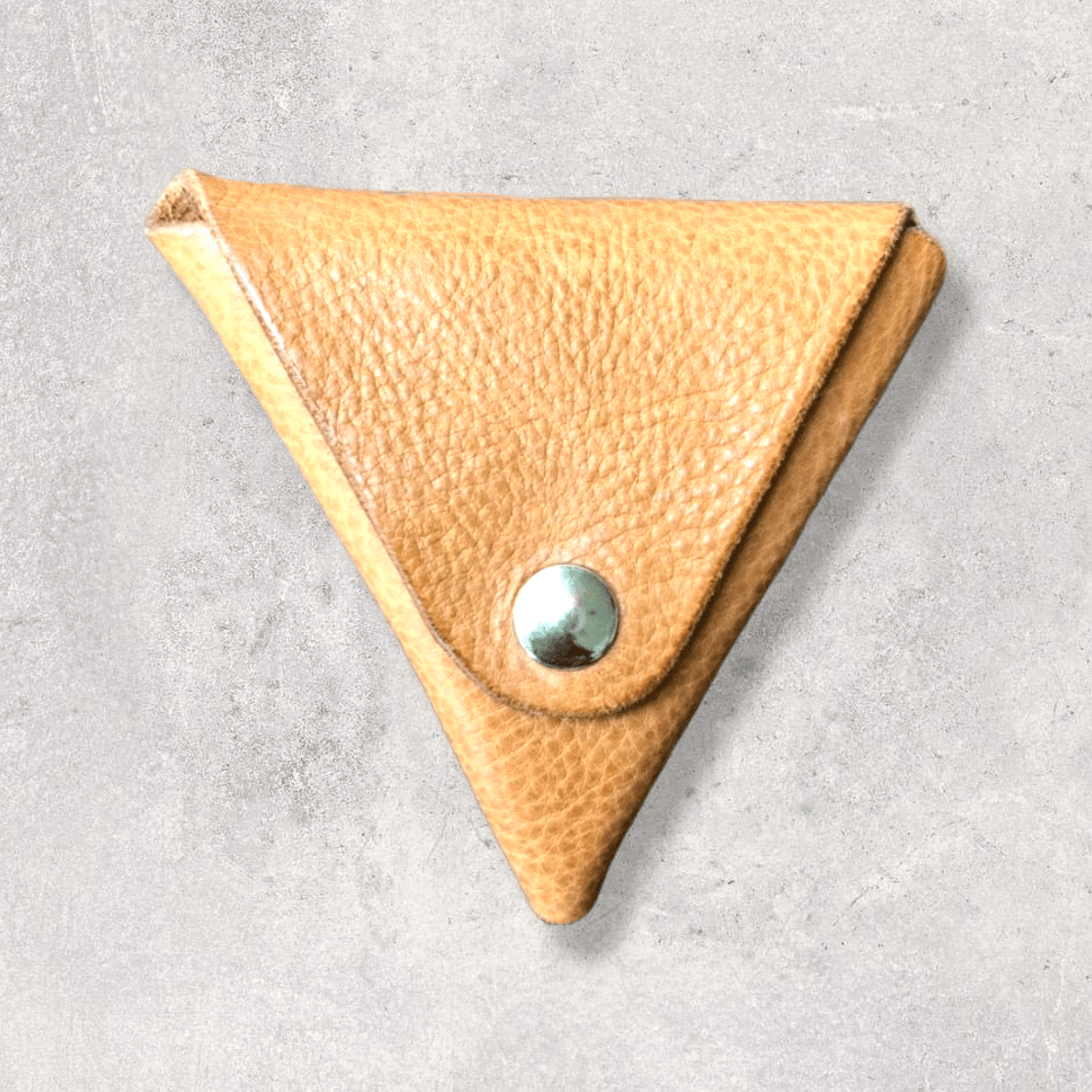 an origami inspired origami triangle shape puse for coins in light tan leather and silver popper